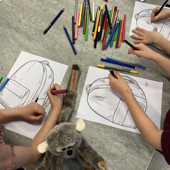Børn farvelægger tegning af skoletaske