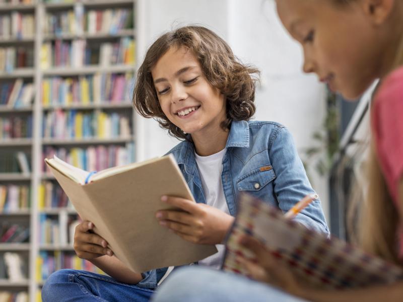 To børn læser i bøger på biblioteket